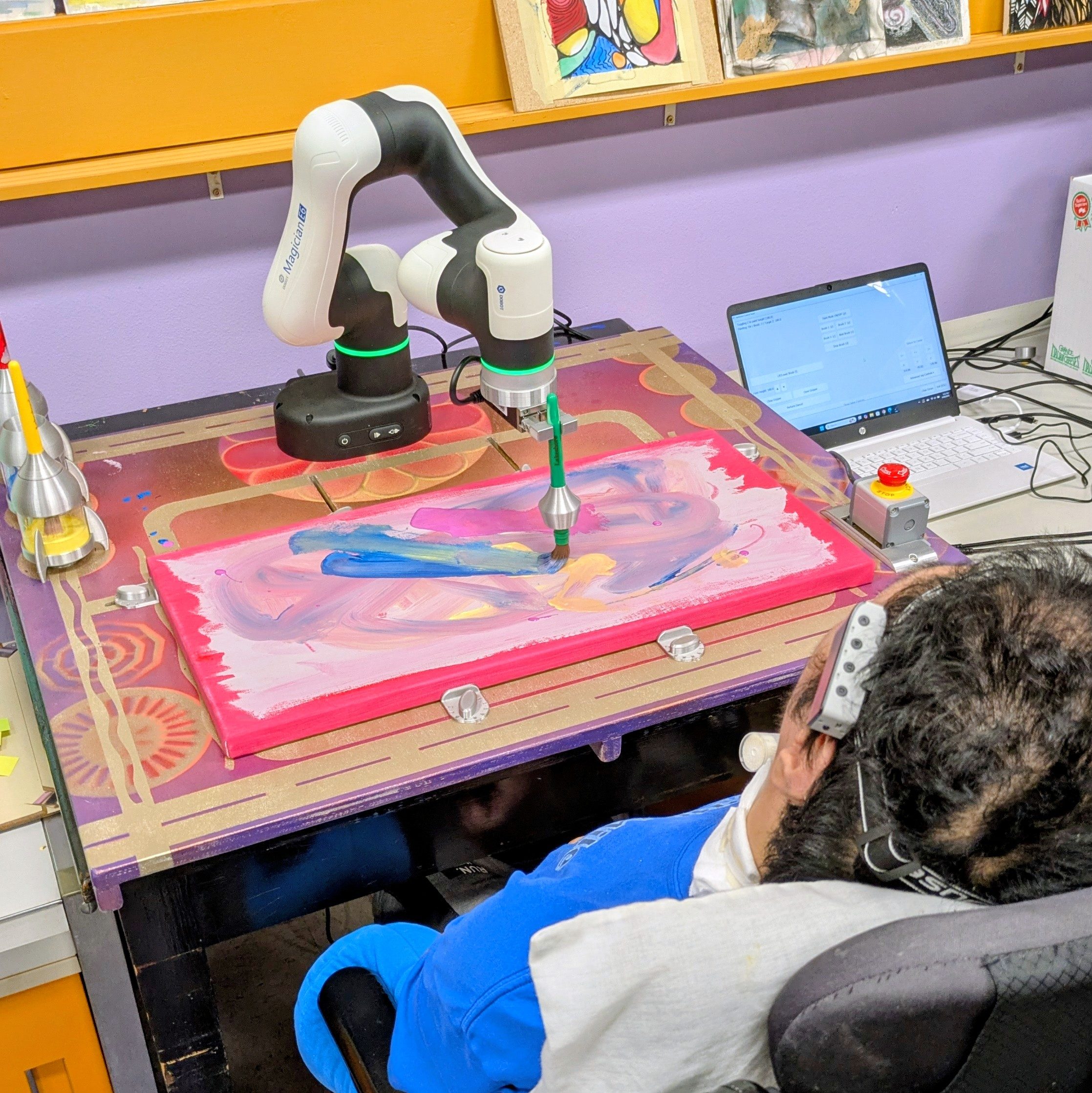 A patron uses their head to control a robotic arm to make a painting at Jump The Moon.